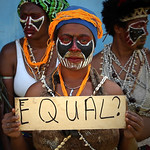 Image of Papuan resident holding handmade sign reading "EQUAL?"